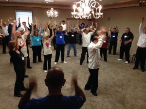 A group of people engaging in a TaiChi coaching conducted in indoor setting